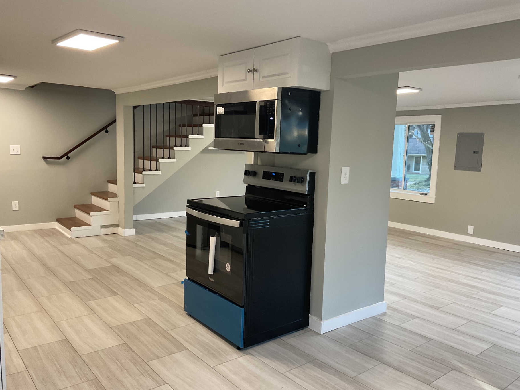 Kitchen area with new stainless range and microwave beside the refinished wood staircase