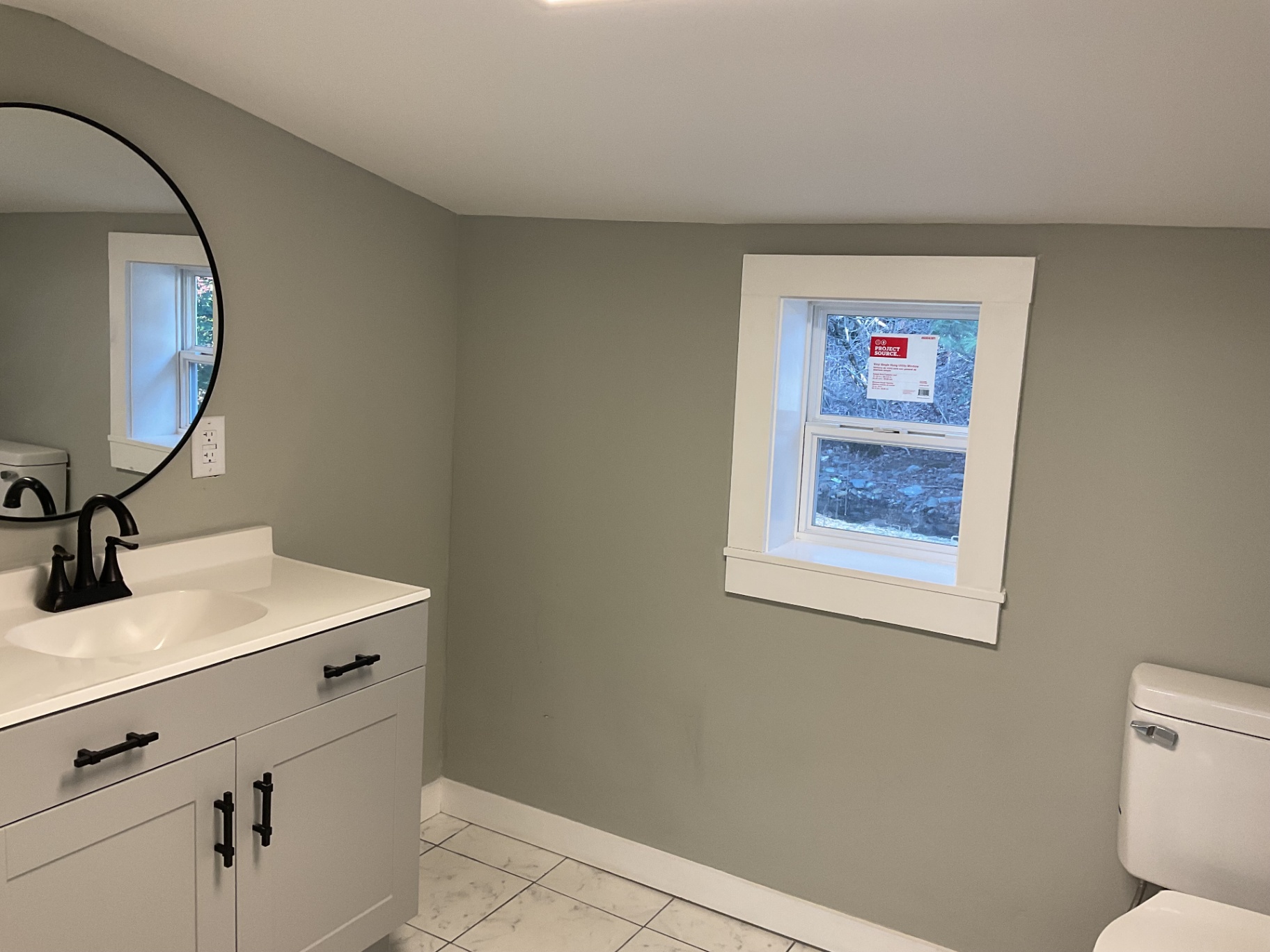Second bathroom with new vanity, round mirror, black hardware, and marble-look tile floor