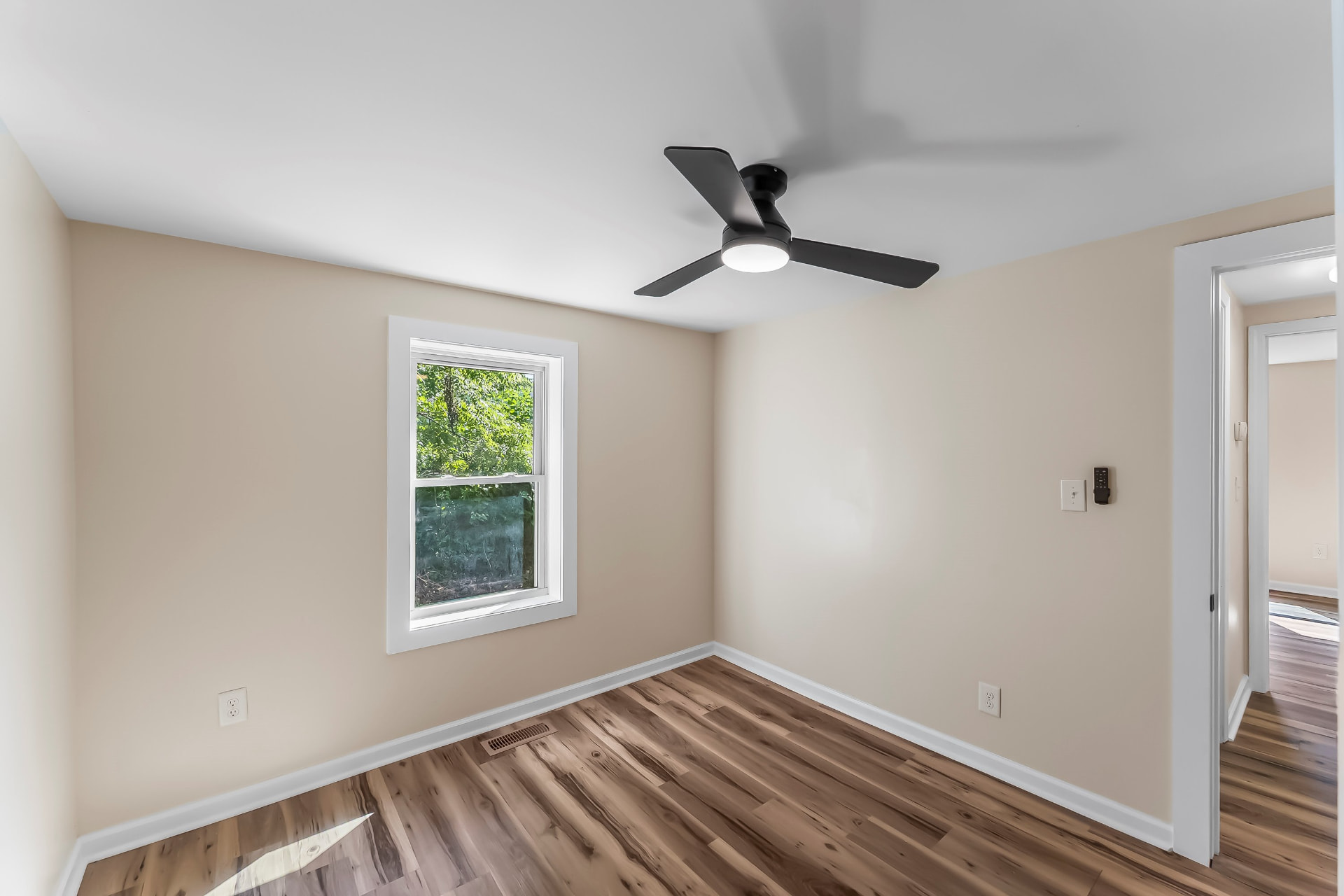 Bright bedroom with new window, wood-look flooring, and ceiling fan