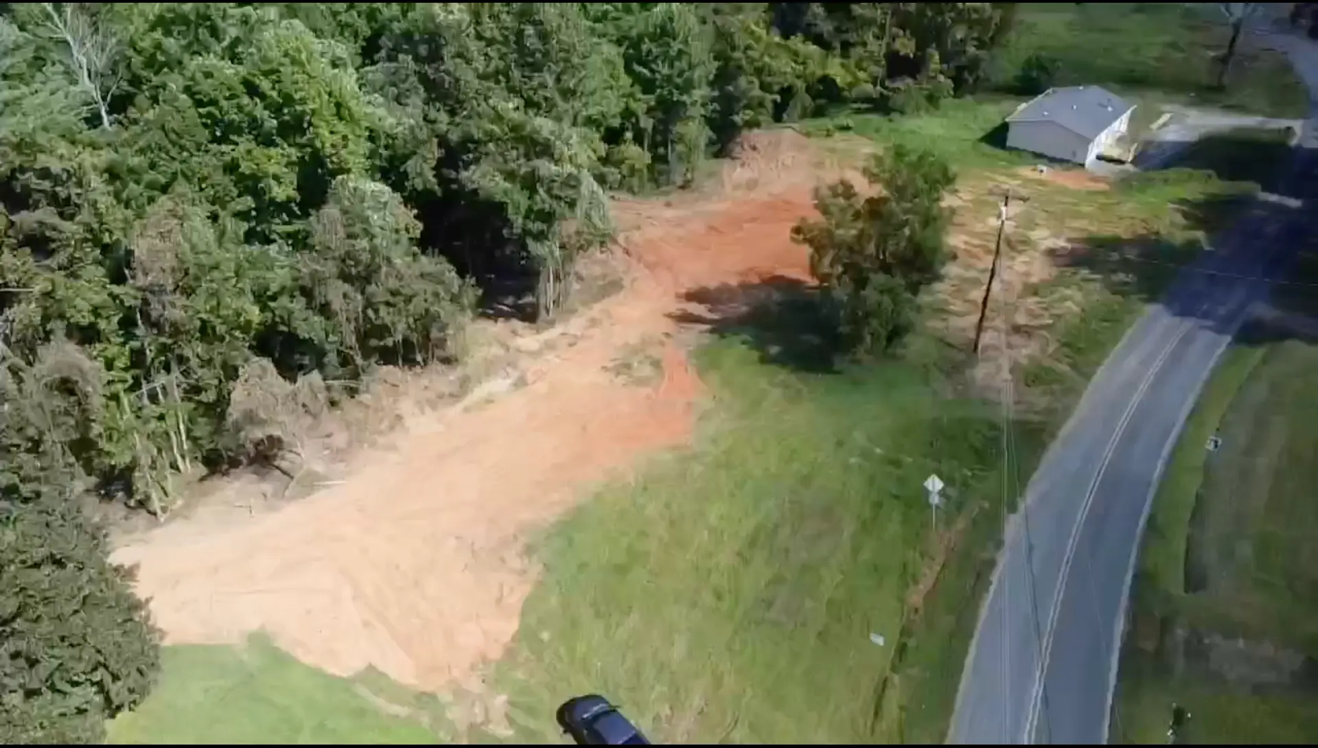 Cleared and graded building lot with new driveway cut along the road