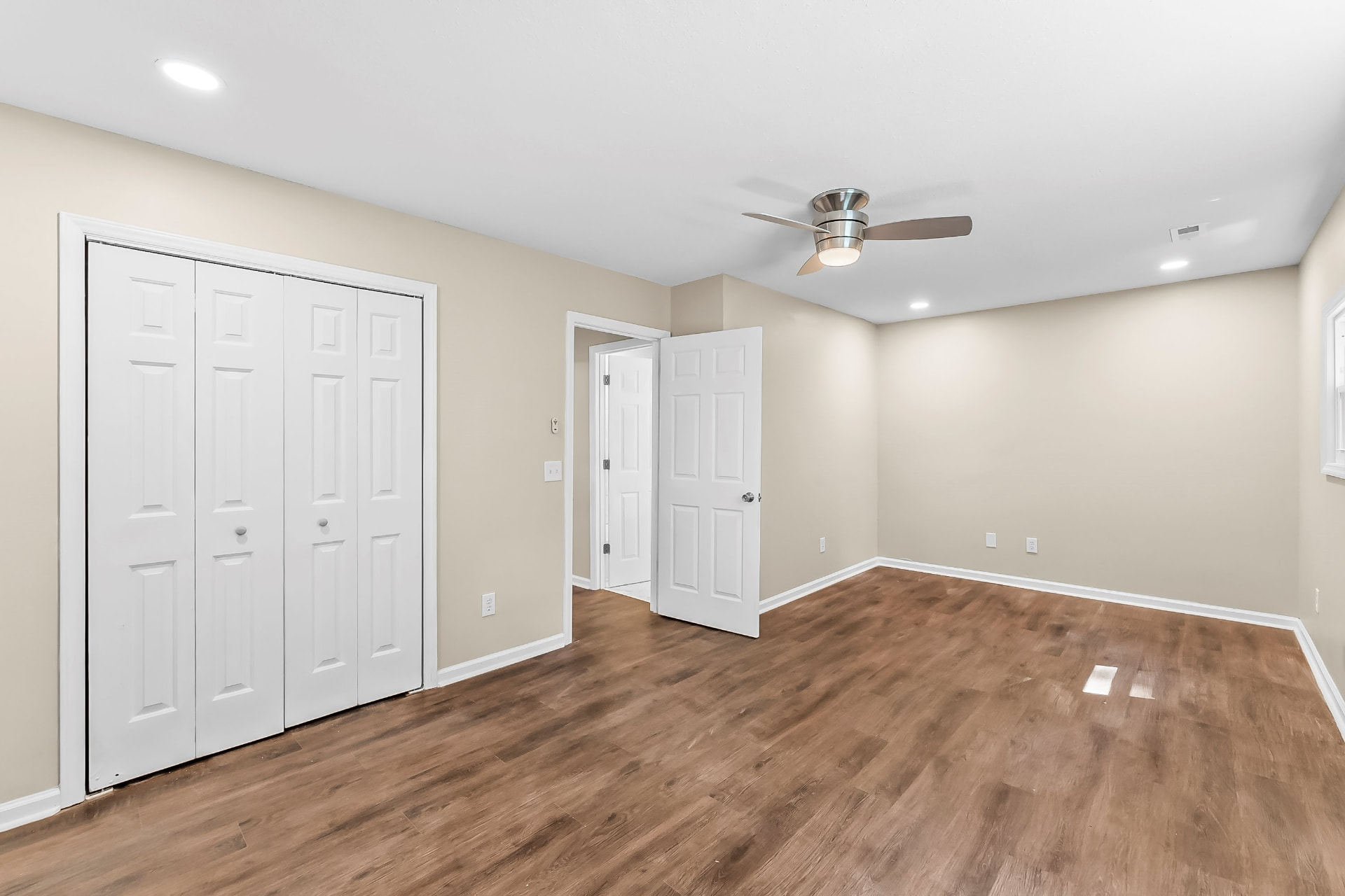 Bedroom with new ceiling fan, double closet doors, and wood-look flooring