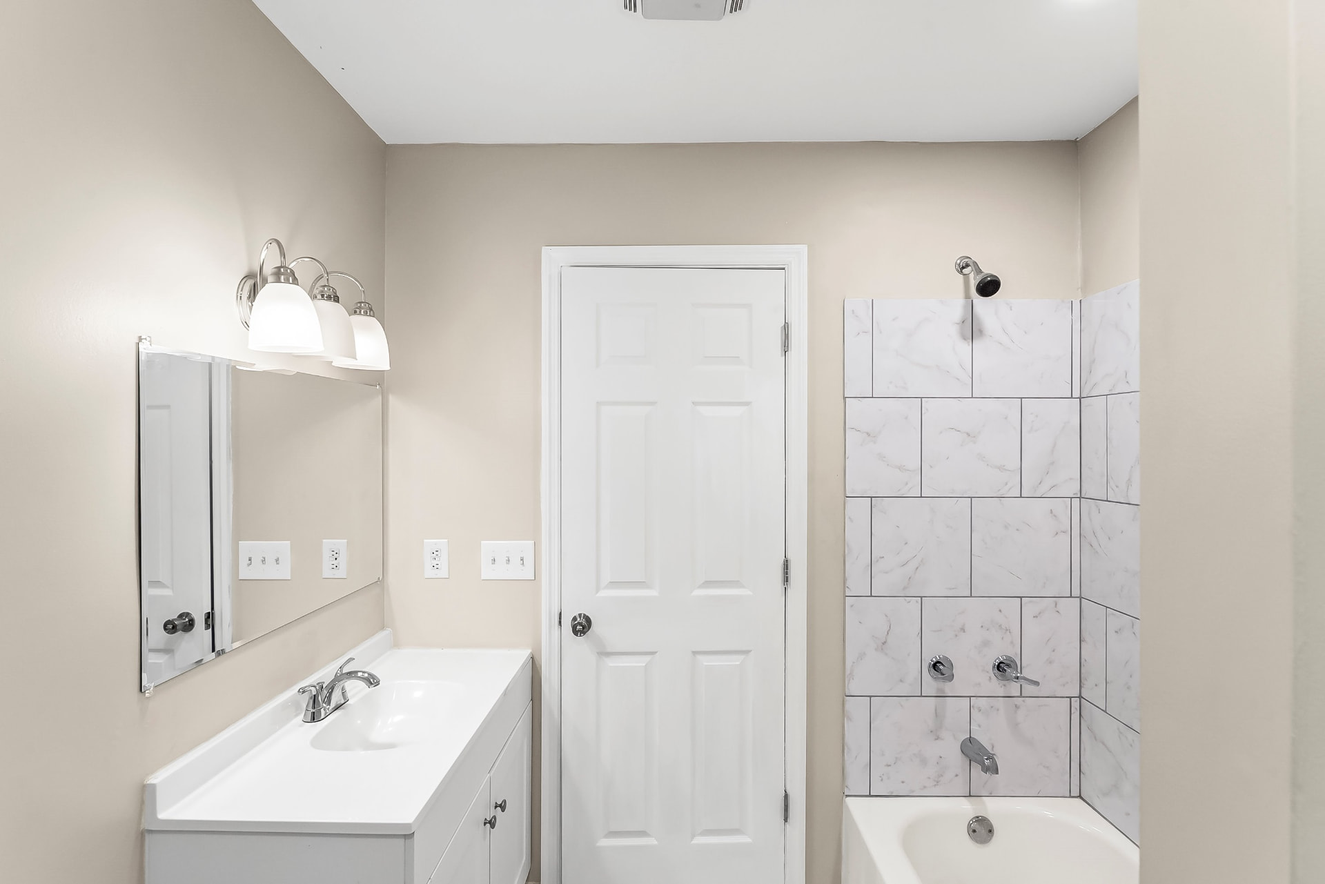 Second bathroom with new vanity, mirror, and tiled tub and shower surround