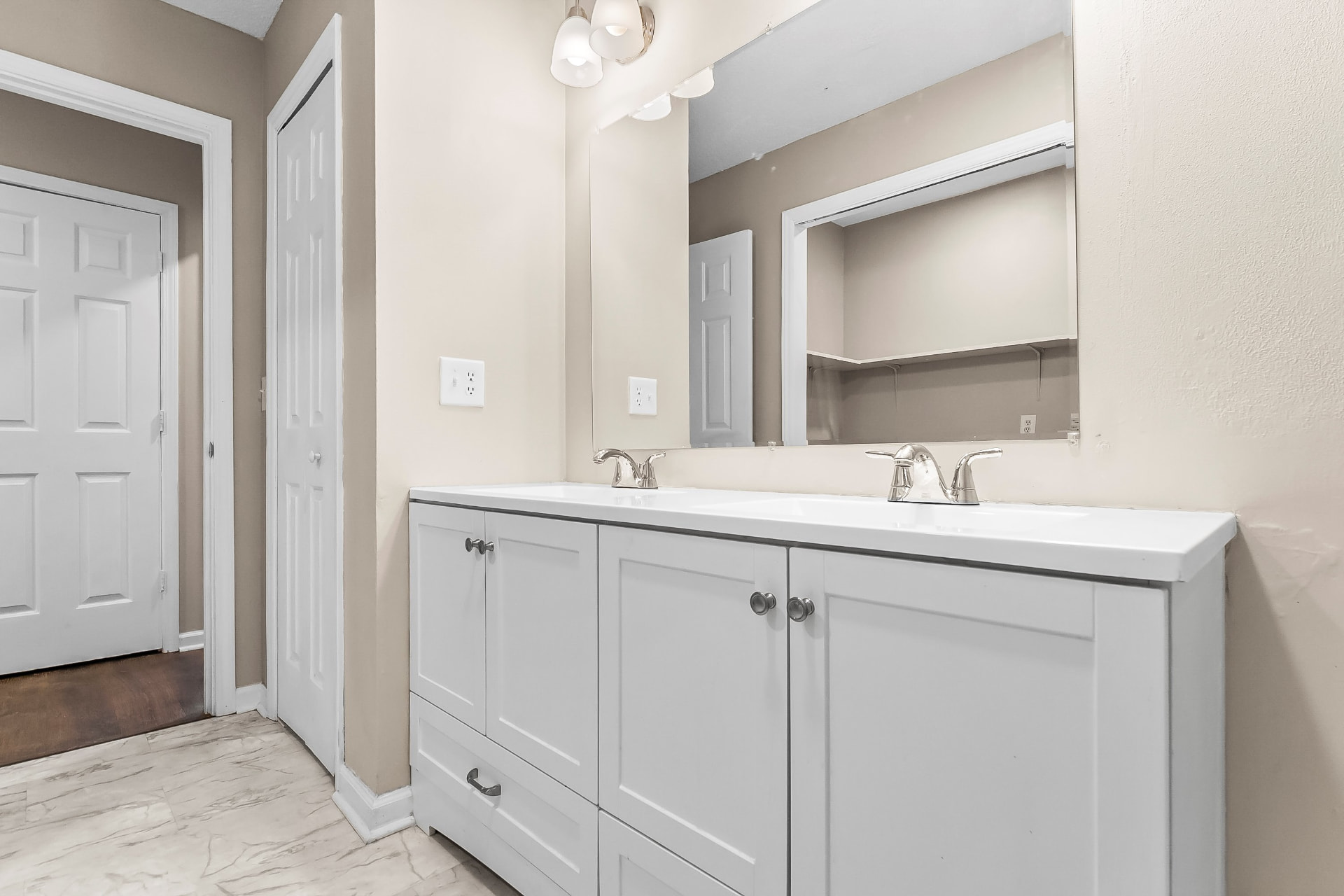 Bathroom with new double-sink vanity, large mirror, and marble-look tile floor