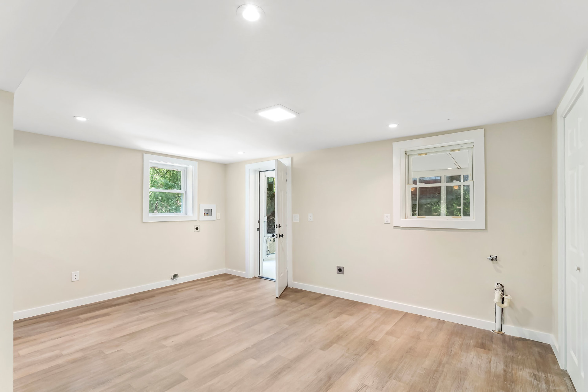 Finished basement room with laundry hookups, new windows, and exterior door