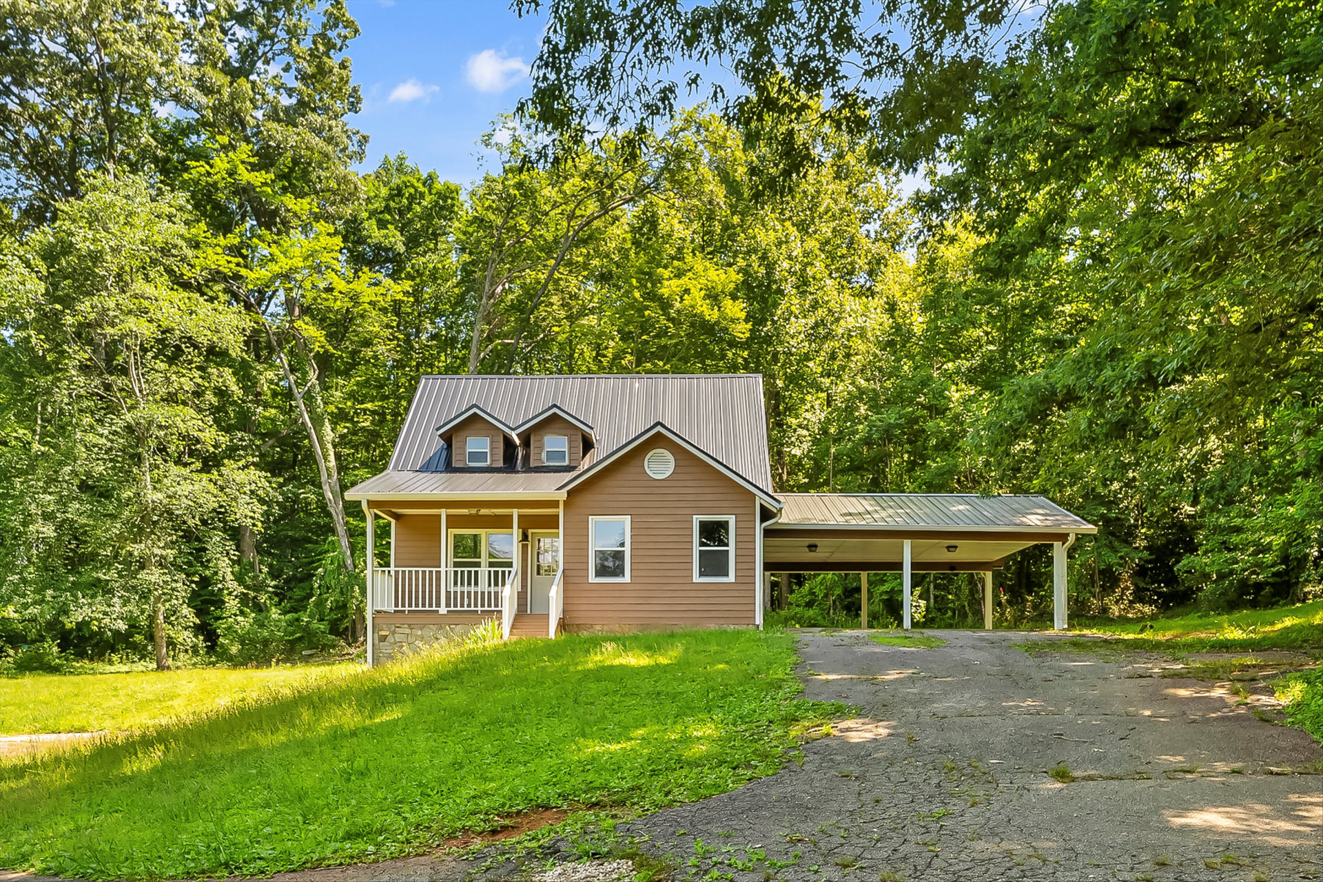 Remodeled cottage-style home with new metal roof, tan siding, covered front porch, and attached carport in Lenoir, NC