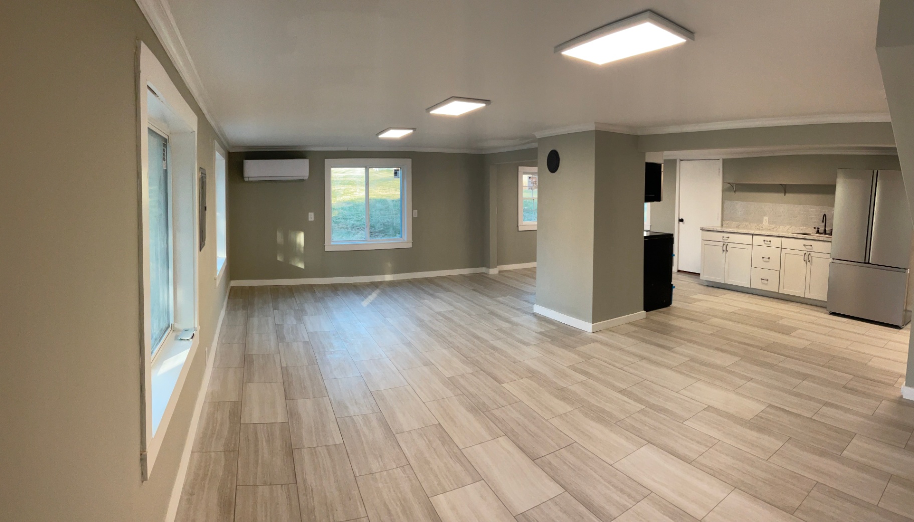 Open remodeled living space in Boone, NC with wood-look tile flooring, crown molding, and kitchenette