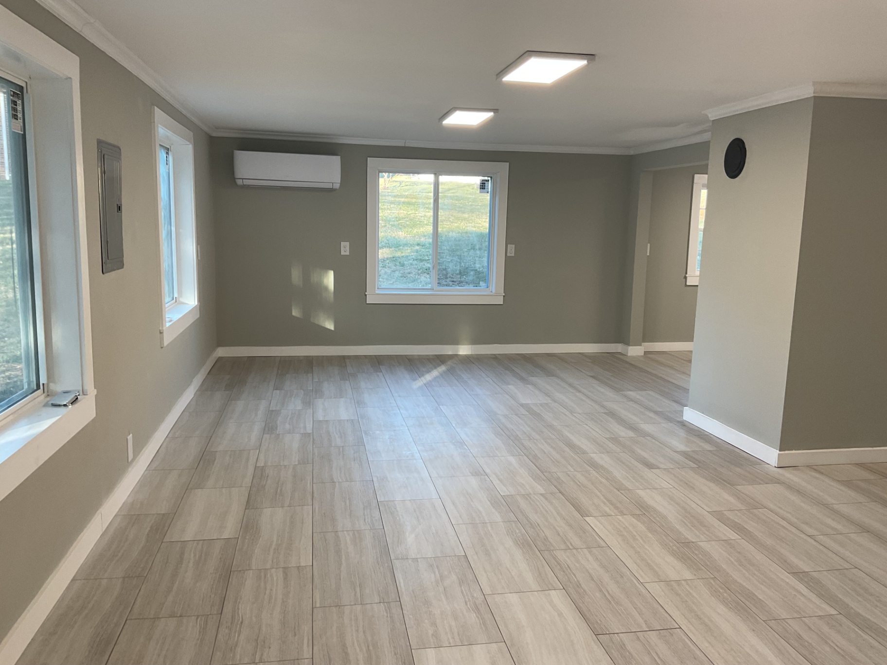 Bright living area with new windows, mini-split heat pump, fresh paint, and tile flooring