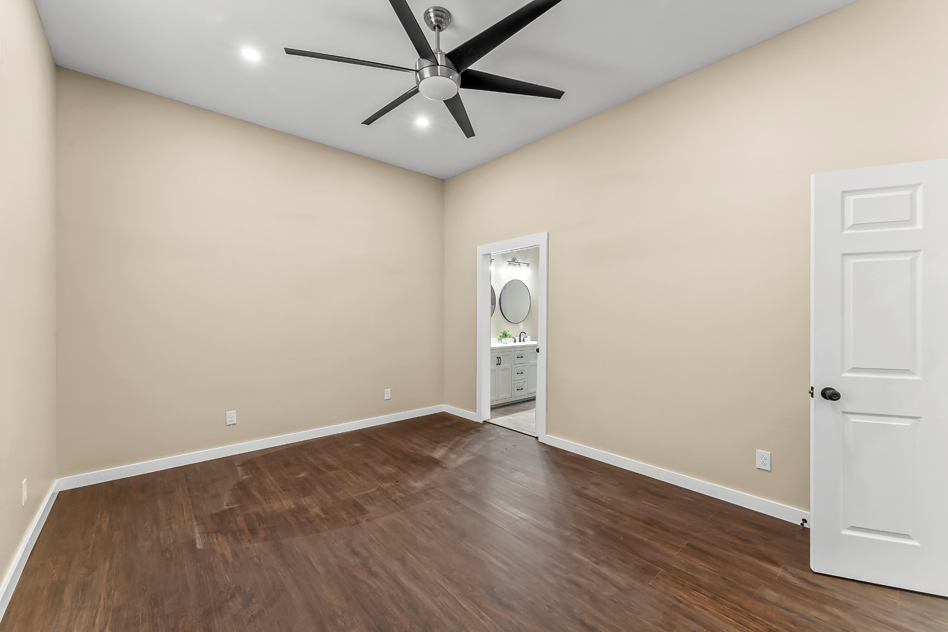 Primary bedroom with ceiling fan and doorway into the en suite bathroom