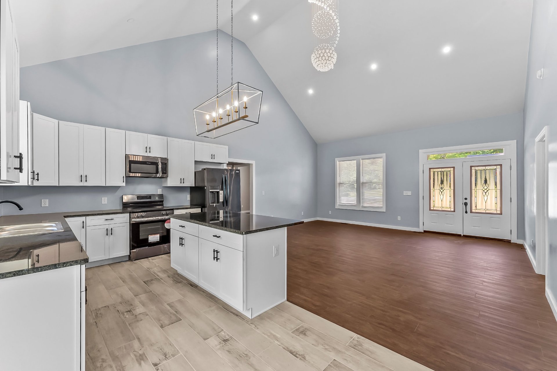 Kitchen and entry with vaulted ceiling, chandelier, and glass double front doors