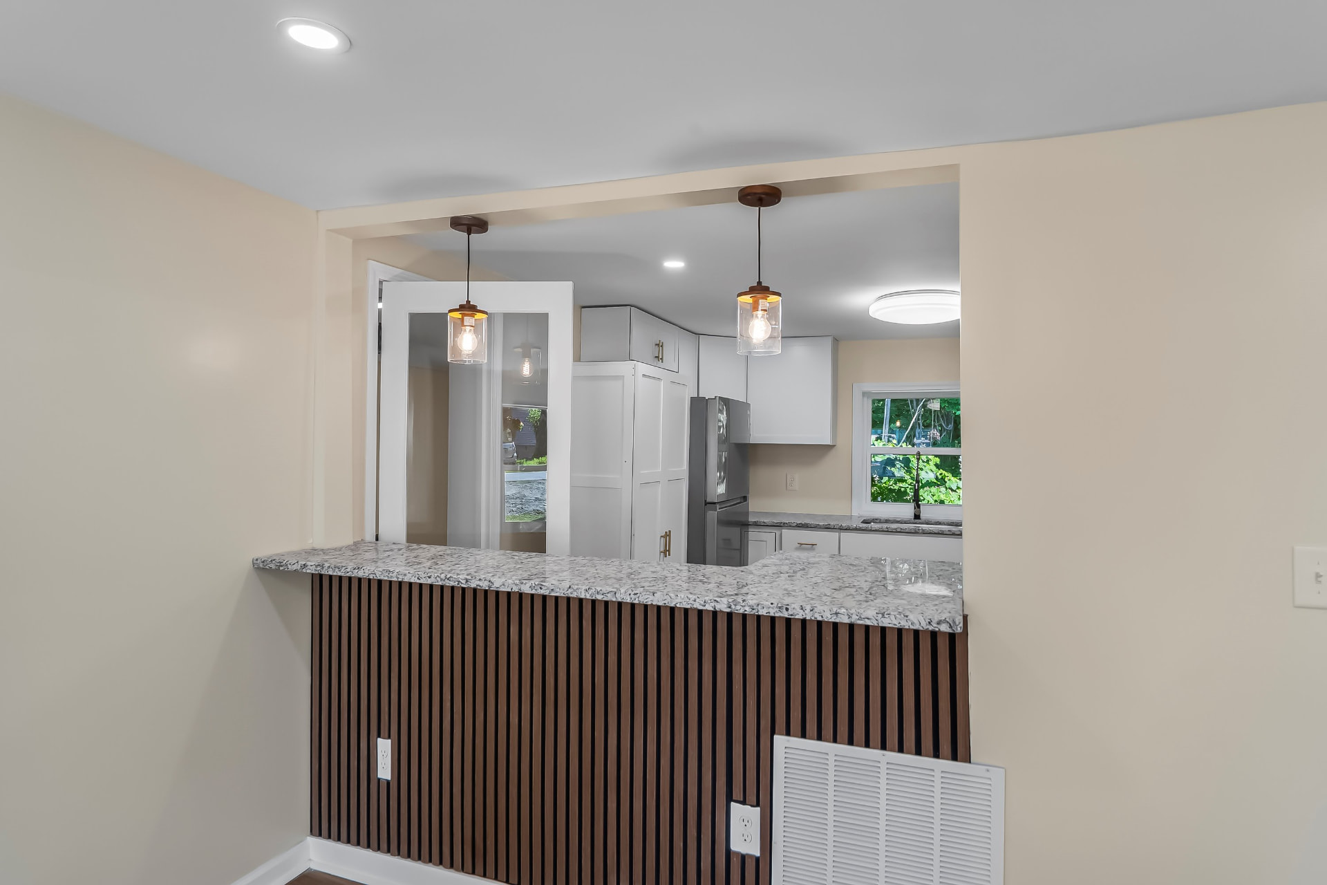 Granite breakfast bar with slatted wood front and glass pendant lighting