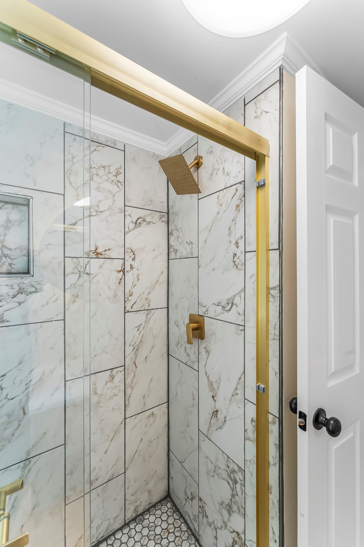 Tiled walk-in shower with marble-look tile and brushed gold fixtures