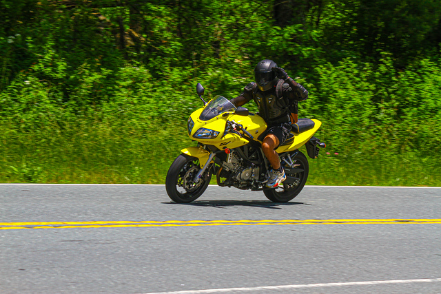 Taha riding a yellow motorcycle on a mountain road