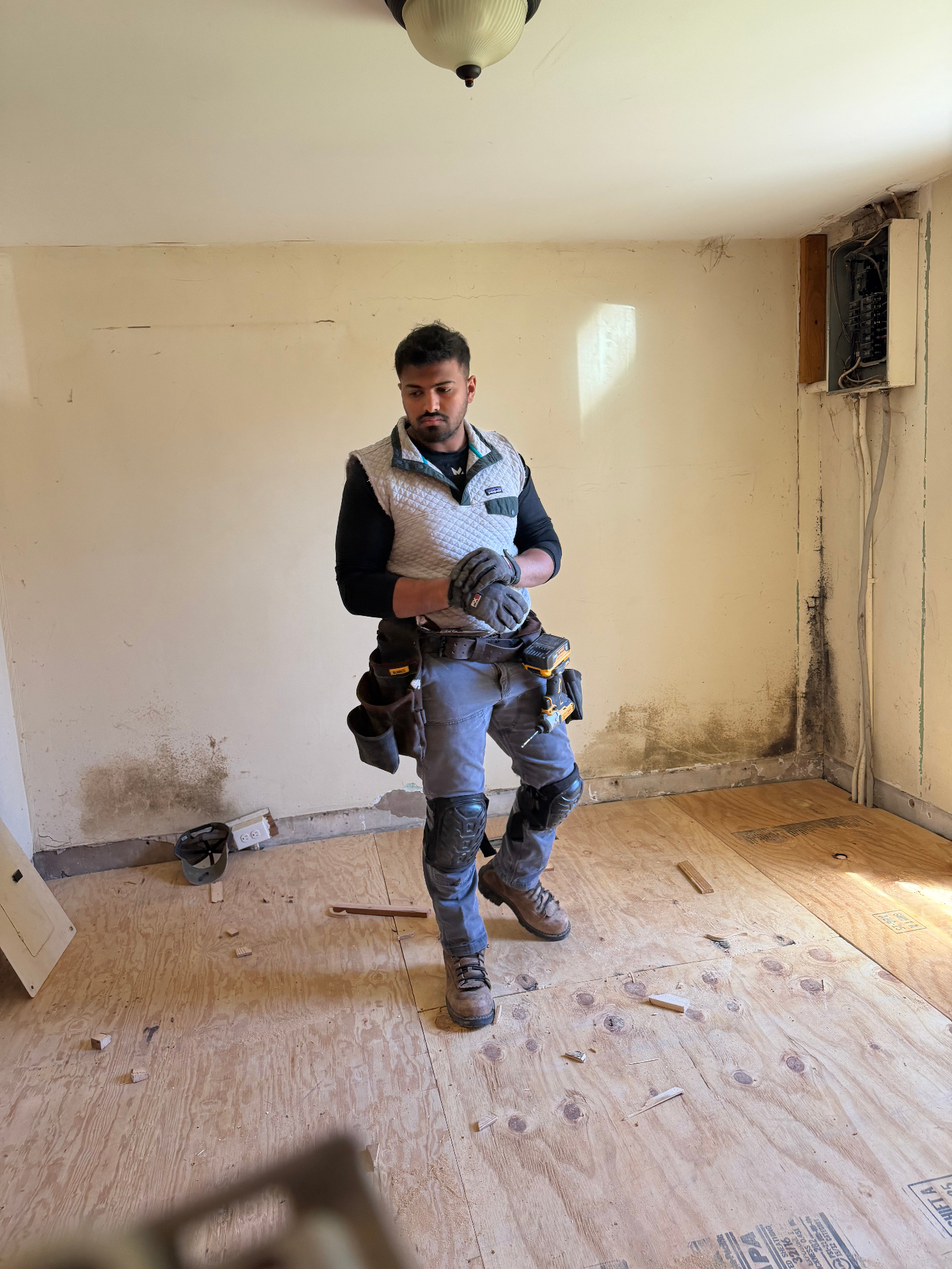 Taha on a job site wearing a tool belt during a home renovation