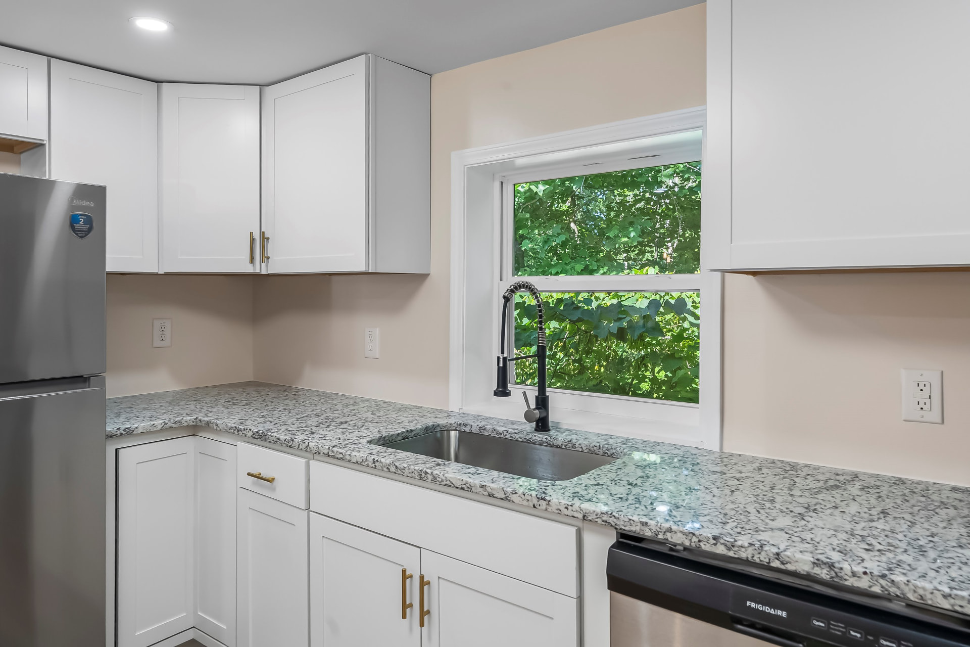 Kitchen sink area with speckled granite counters and a black spring faucet