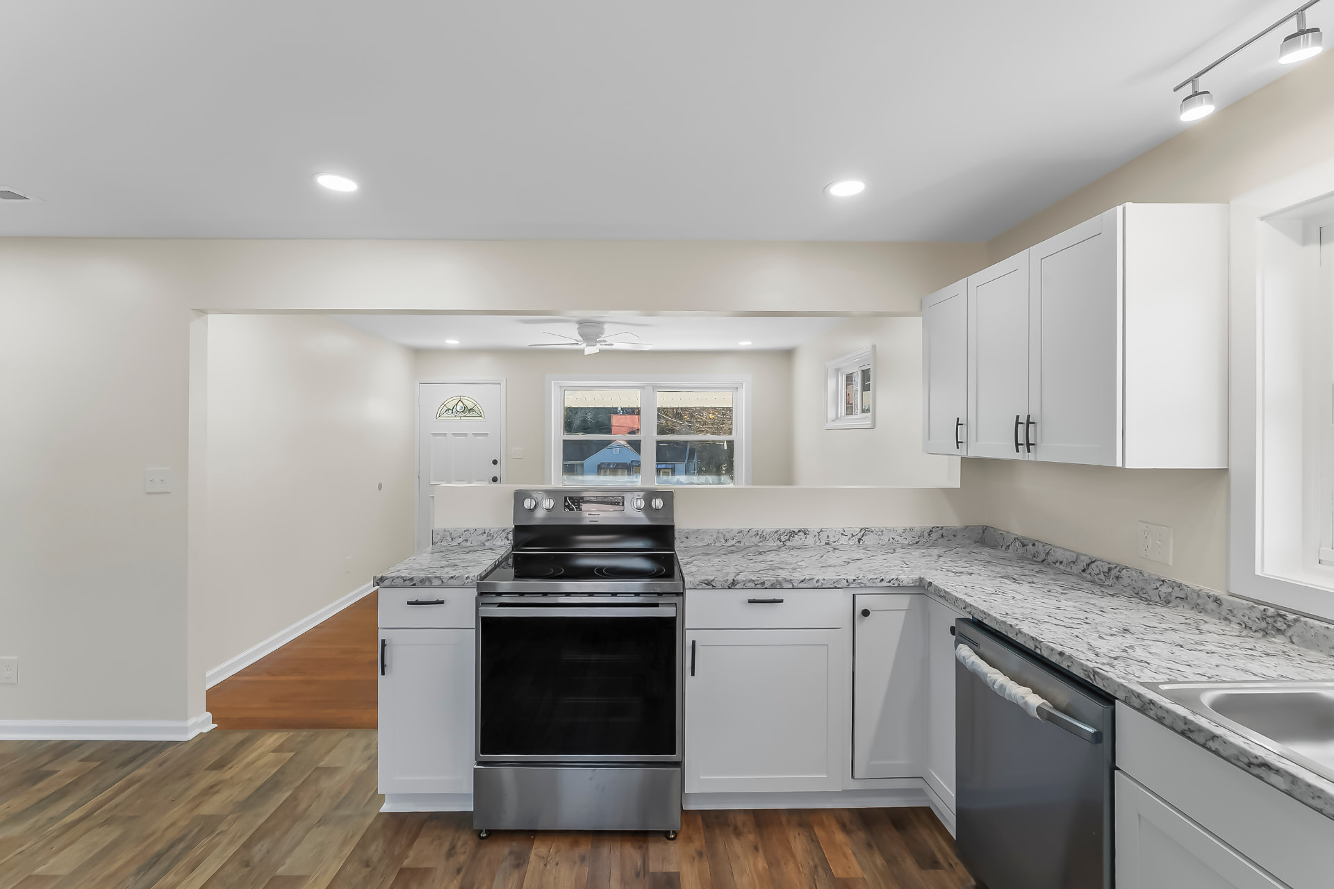 Kitchen range and counter run with track lighting and vinyl plank flooring