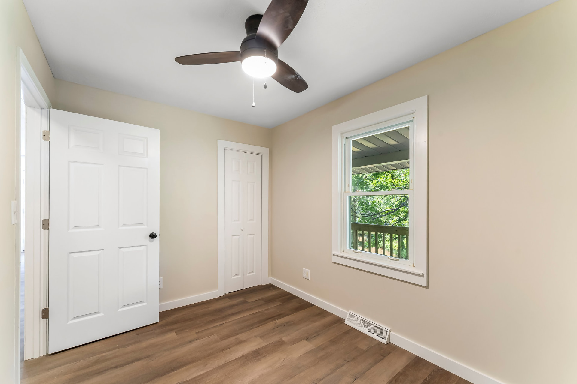 Bedroom with fresh paint, new ceiling fan, closet doors, and wood-look flooring