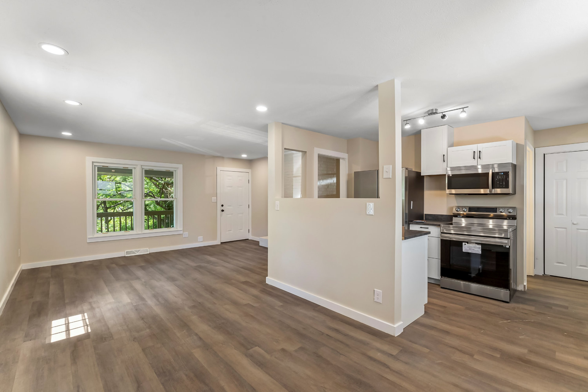 Open main-level living room and kitchen with new wood-look flooring, recessed lighting, and white cabinets