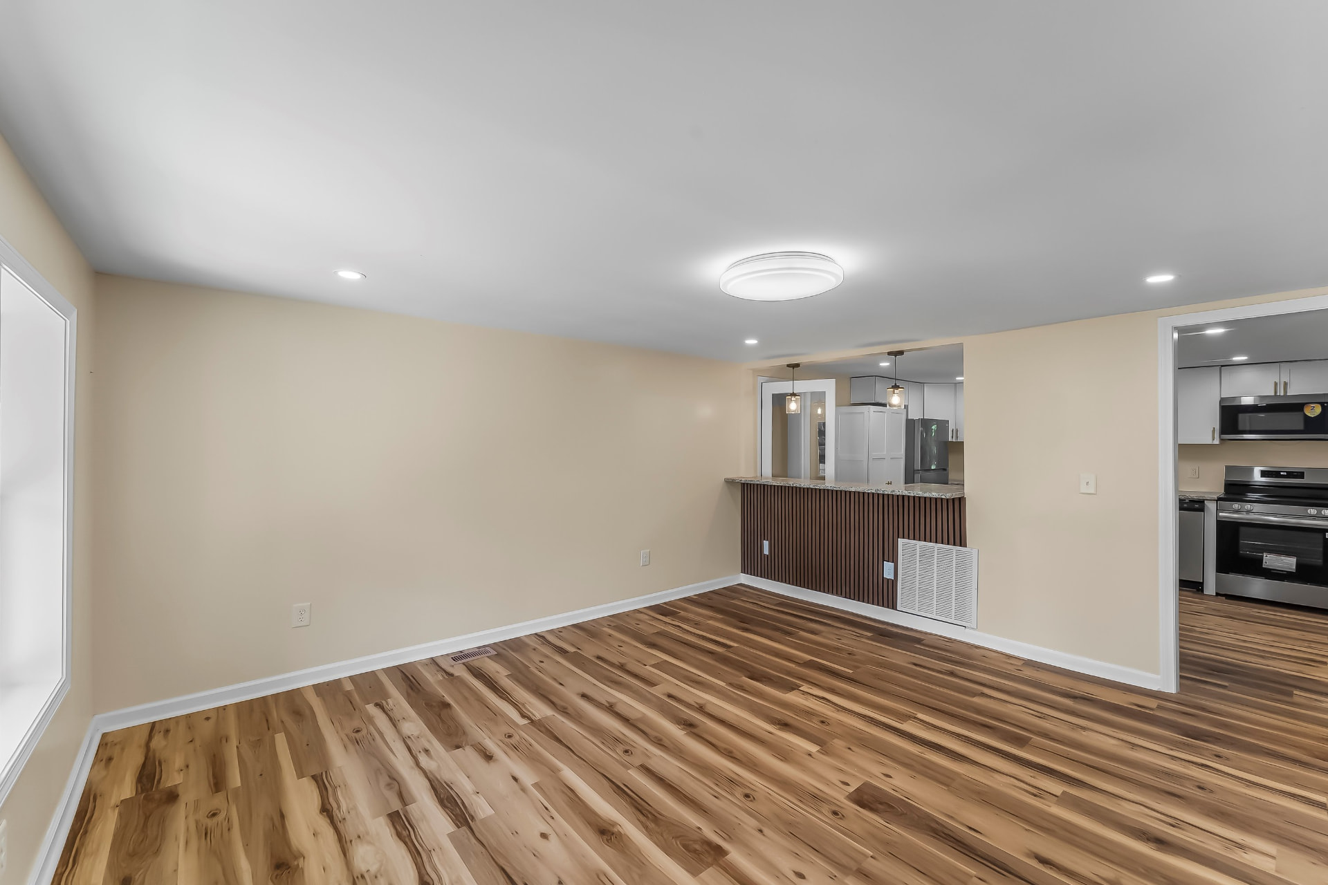 Open living room with new hickory-tone flooring opening onto the kitchen
