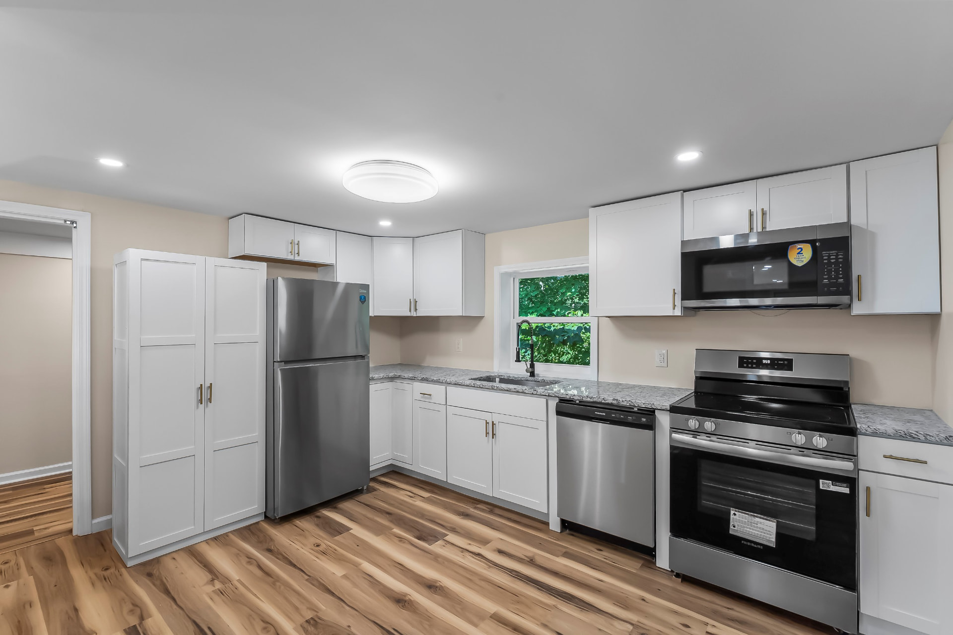 New kitchen with white shaker cabinets, granite counters, and stainless appliances