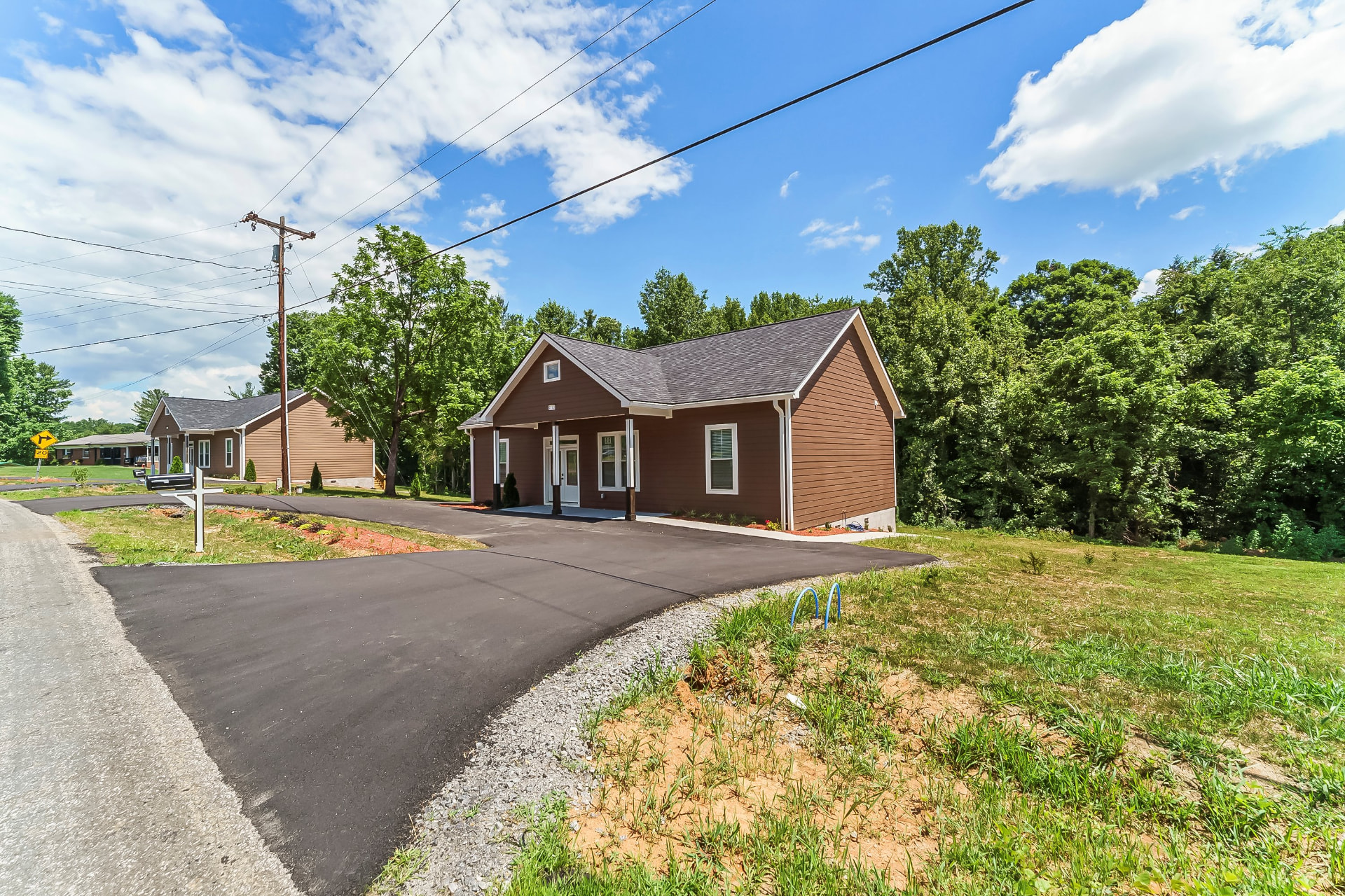 Completed brown craftsman home with covered front porch and new asphalt driveway