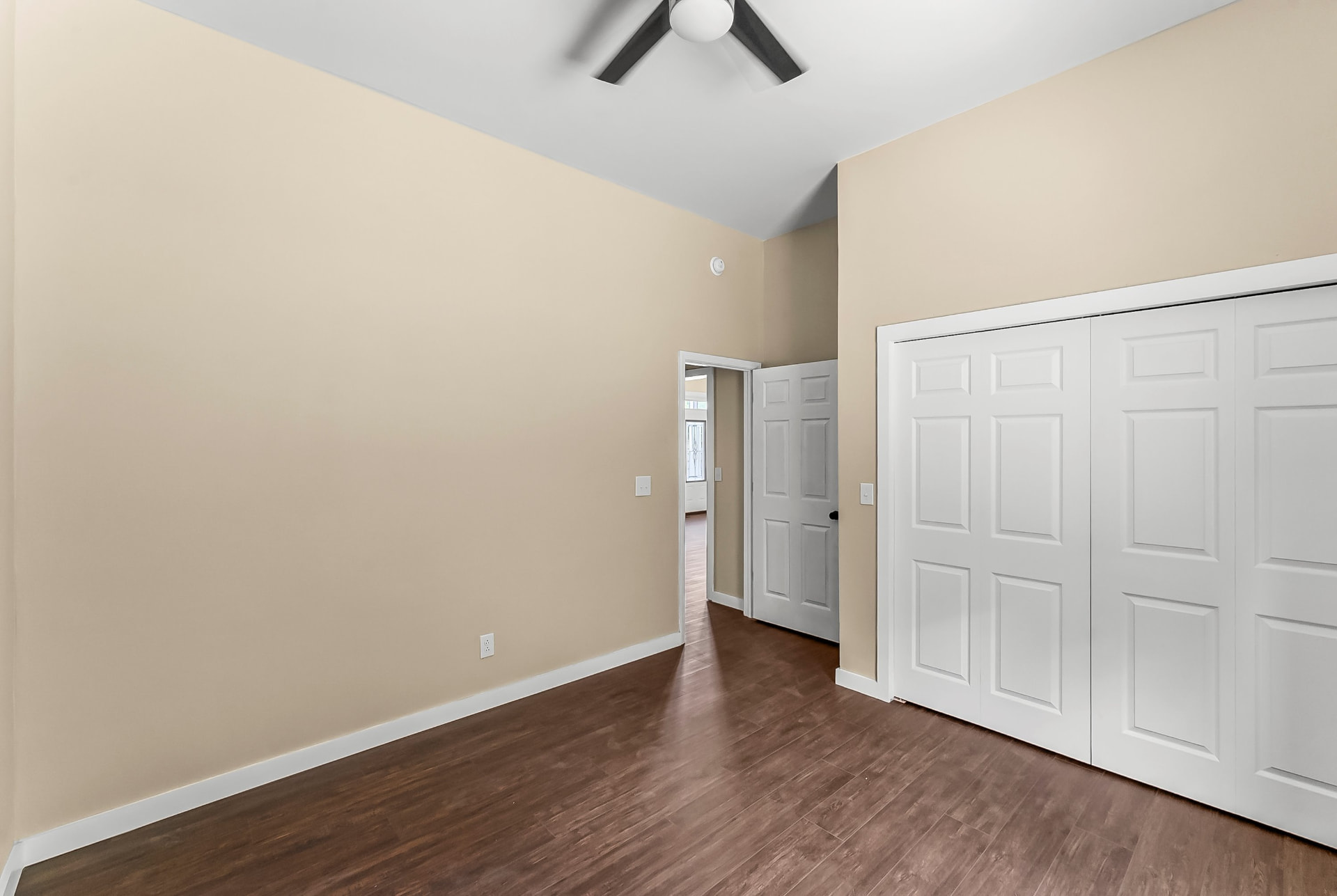 Bedroom with vaulted ceiling, ceiling fan, and double closet doors