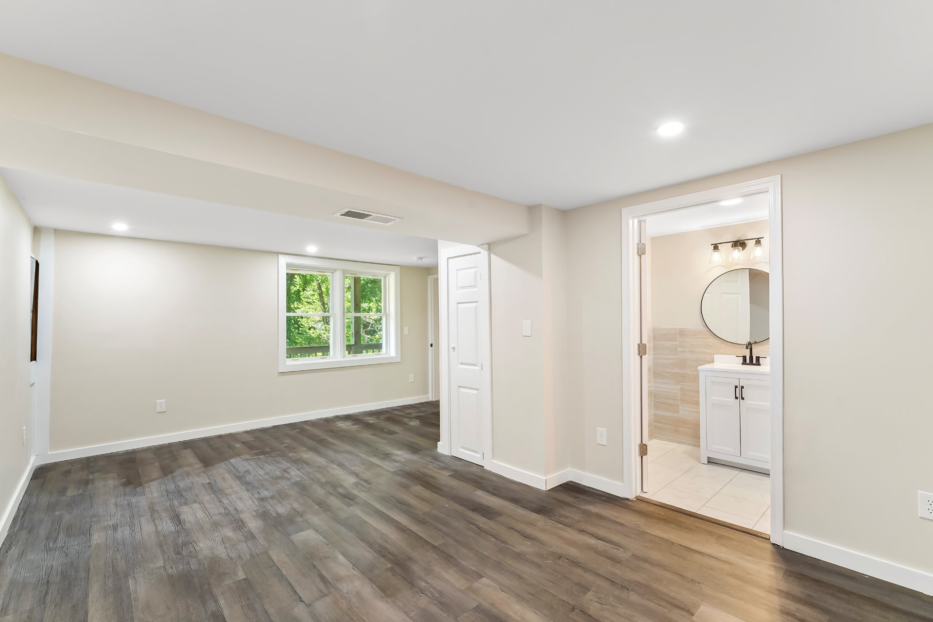 Finished basement suite with wood-look flooring opening into a new full bathroom